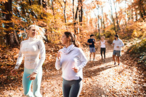 Small group of happy friends running in the woods in the autumn